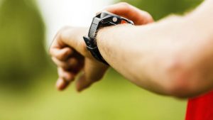 Trail or cross country runner on mountain path looking at sportwatch, checking performance or heart rate pulse. Goal achievement, sport and fitness concept outdoors in nature.