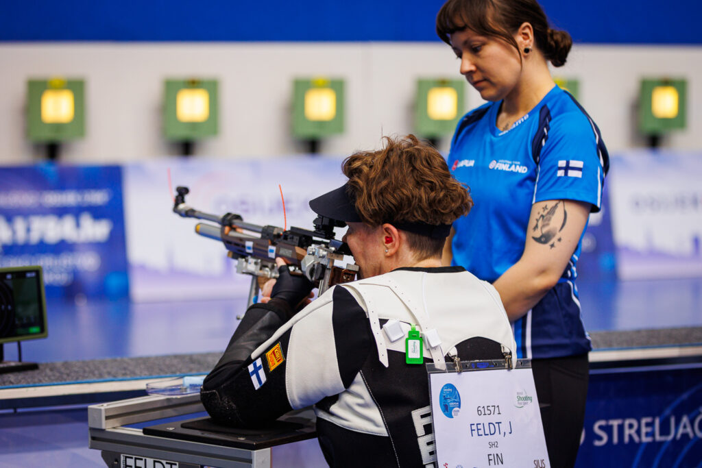 Jaana Feldt ampuu, vieressä avustaja